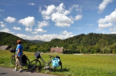 Zwei Räder sind am Straßenrand abgestellt und eine Frau blickt in die Landschaft