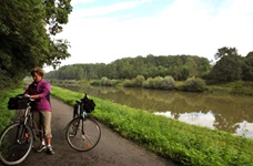 Eine Fahrradfahrerin steht auf dem Radweg an der Rhone