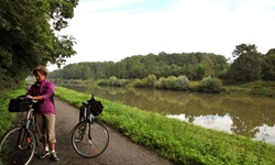 Eine Fahrradfahrerin steht auf dem Radweg an der Rhone