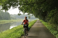 Eine Radlerin fährt auf dem Rhone-Radweg dem Fluss entlang