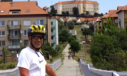 Ein Fahrradfahrer steht auf einer Brücke in Mikulov in Tschechien - im Hintergrund ist das gleichnamige Schloss zu sehen