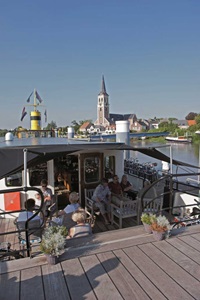 Gäste sitzen auf gemütlichen Möbeln unter einem Sonnensegel an Deck der MS Princesse Royale