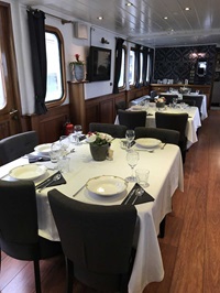 Drei gedeckte Tische mit Blumenschmuck im Restaurant der MS Princesse Royale