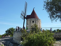 Touristen stehen vor einer aus stein erbauten Windmühle