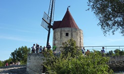 Touristen stehen vor einer aus stein erbauten Windmühle