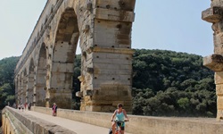 Eine Radlerin überquert die bekannte Römerbrücke Pont du Gard