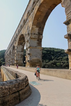 Eine Radlerin überquert die bekannte Römerbrücke Pont du Gard