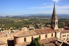 Die Kirche von Saint-Saturnin-les-Apt vor dem wunderschönen Panorama des Naturparks Lubéron.