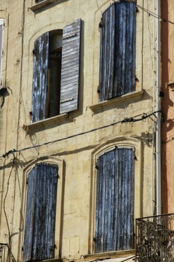 Blau gestrichene Holzfensterläden an einem ockerfarbenen Haus in der Provence.