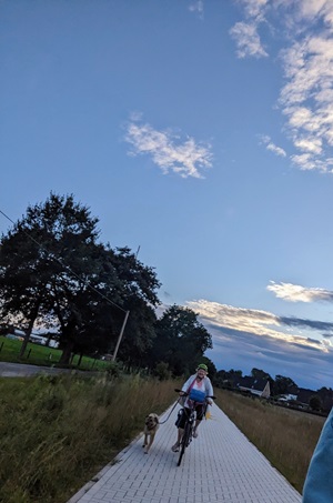 Eine Fahrradfahrerin mit ihrem Hund auf dem Etschtal-Radweg