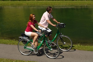 Eine Frau und ein Mann radeln auf einem Radweg an einem Fluss entlang