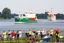 Eine Gruppe Radfahrer auf dem Radweg am Nord-Ostsee-Kanal - auf dem Kanal sind zwei Schiffe zu sehen