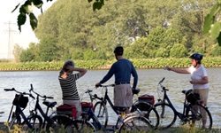 Drei Radfahrer machen pause an einem Fluss in Holland