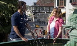 Zwei Radler haben ihre Räder abgestellt und erfrischen sich am Andreasbrunnen in Deidesheim.