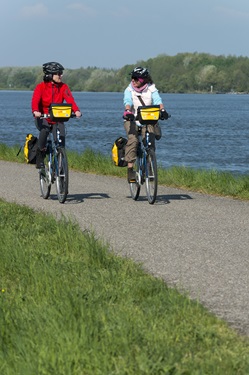 Zwei Radlerinnen radeln am Donauufer entlang und unterhalten sich angeregt.