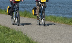 Zwei Radlerinnen radeln am Donauufer entlang und unterhalten sich angeregt.