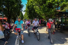 Eine Radlergruppe fährt an einem ungarischen Markt vorbei.