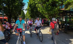 Eine Radlergruppe fährt an einem ungarischen Markt vorbei.