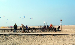 Blick auf einen Radler-Strand mit vielen abgestellten Rädern und einige Fahrradfahrern