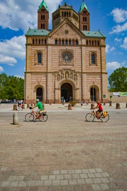 Zwei Radler fahren am Speyerer Dom vorbei.