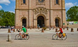Zwei Radler fahren am Speyerer Dom vorbei.