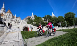 Drei Radler fahren an der Fischerbastei und der Matthiaskirche in Budapest vorbei.