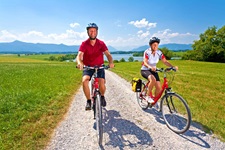 Zwei Radler sind auf einem weiß gekiesten Radweg im bayerischen Fünf-Seen-Land unterwegs.