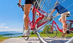 Zwei Radler fahren im bayerischen Voralpenland auf einen See zu.