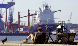Ein Radler macht am Hafen von Kiel Pause und schaut sich eine Karte an