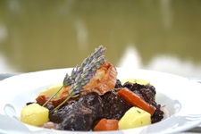 Eine Portion Boeuf Bourguignon mit Möhren, Kartoffeln und zwei dekorativen Lavendelzweigen.