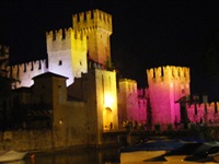 Das in verschiedenen Farben angestrahlte Castello Scaligero - die Burg von Sirmione.
