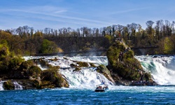 Ein Ausflusgboot mit Touristen besucht den Rheinfall bei Schaffhausen