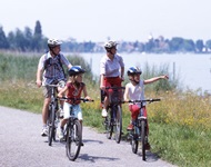 Eine Familie mit 2 Kindern radelt am Bodensee entlang.