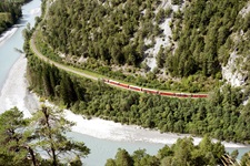 Blick in die verträumte Rheinschlucht, in der ein Zug durchfährt, auf der Rhein-Route