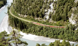Blick in die verträumte Rheinschlucht, in der ein Zug durchfährt, auf der Rhein-Route