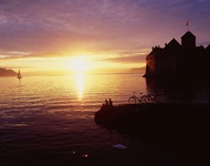 Ein Pärchen sitzt bei Schloss Chillon am Ufer des Genfersees und erfreut sich an einem wunderschönen Sonnenuntergang.