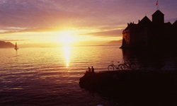 Ein Pärchen sitzt bei Schloss Chillon am Ufer des Genfersees und erfreut sich an einem wunderschönen Sonnenuntergang.