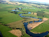 Eine Luftaufnahme der sich durch Felder und Wiesen schlängelnden Maas.