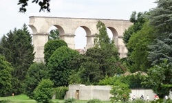 Ein noch teilweise erhaltenes Aquädukt bei Ars-sur-Moselle wird dekorativ von Bäumen eingerahmt.