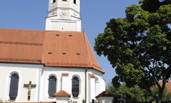 Die Klosterkirche Andechs an der ein Fahrradfahrer vorbei fährt