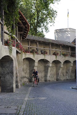 Ein Radfahrer fährt auf einer Straße mit Kopfsteinpflaster an einer Mauer im Schongau entlang