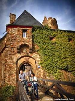 Zwei Radfahrer stehen auf der Brücke der Burg Thurant und planen die heutige Tagestour anhand einer Infobroschüre.