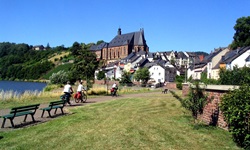 Drei Radler steuern ein Dorf am Saar-Mosel-Radweg an.