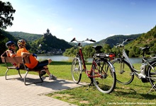 Zwei Radfahrer machen auf einer Bank an der Mosel ein Verschnaufpause