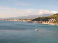 Wunderschöner Panoramablick auf das türkisblau schimmernde Meer und den dahinter liegenden, mit Schnee bedeckten Gipfel des Ätna.
