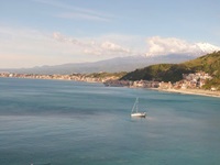 Wunderschöner Panoramablick auf das türkisblau schimmernde Meer und den dahinter liegenden, mit Schnee bedeckten Gipfel des Ätna.