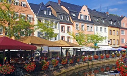Mit roten Blumen geschmückter Kanal der Mosel mit Blick auf die Promenade von Saarburg