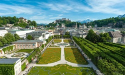 Wunderschöne Stadtansicht von Salzburg mit der gleichnamigen Festung und dem Dom im Hinter- sowie dem prächtig bepflanzten Mirabellgarten im Vordergrund.