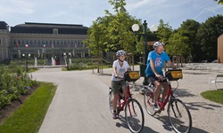 Zwei Radfahrer - ein Mann und eine Frau - auf einem asphaltierten Radweg beim Casino von Bad Ischl.