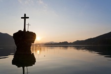 Sonnenuntergang am Mondsee mit Blick auf eine Felsen mit zwei Kreuzen